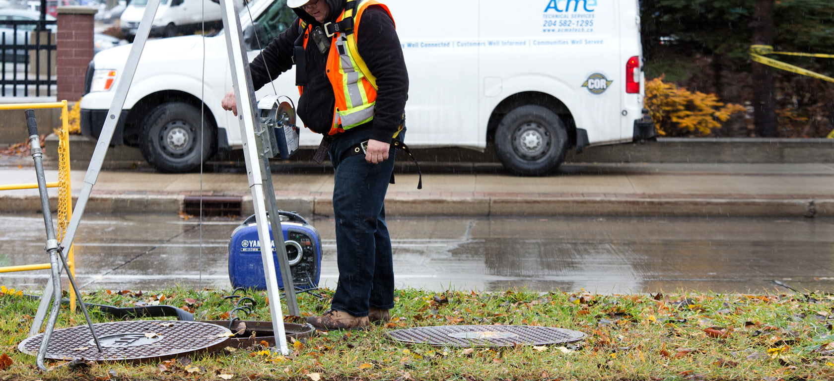 A man monitoring a coworker in a manhole.